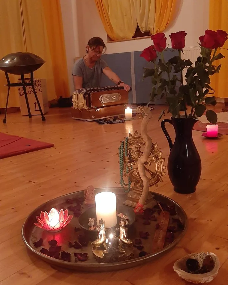 Kerzen, Rosen und eine Handpan in einem Yogaraum, im Hintergrund Werner Hauschild am Harmonium